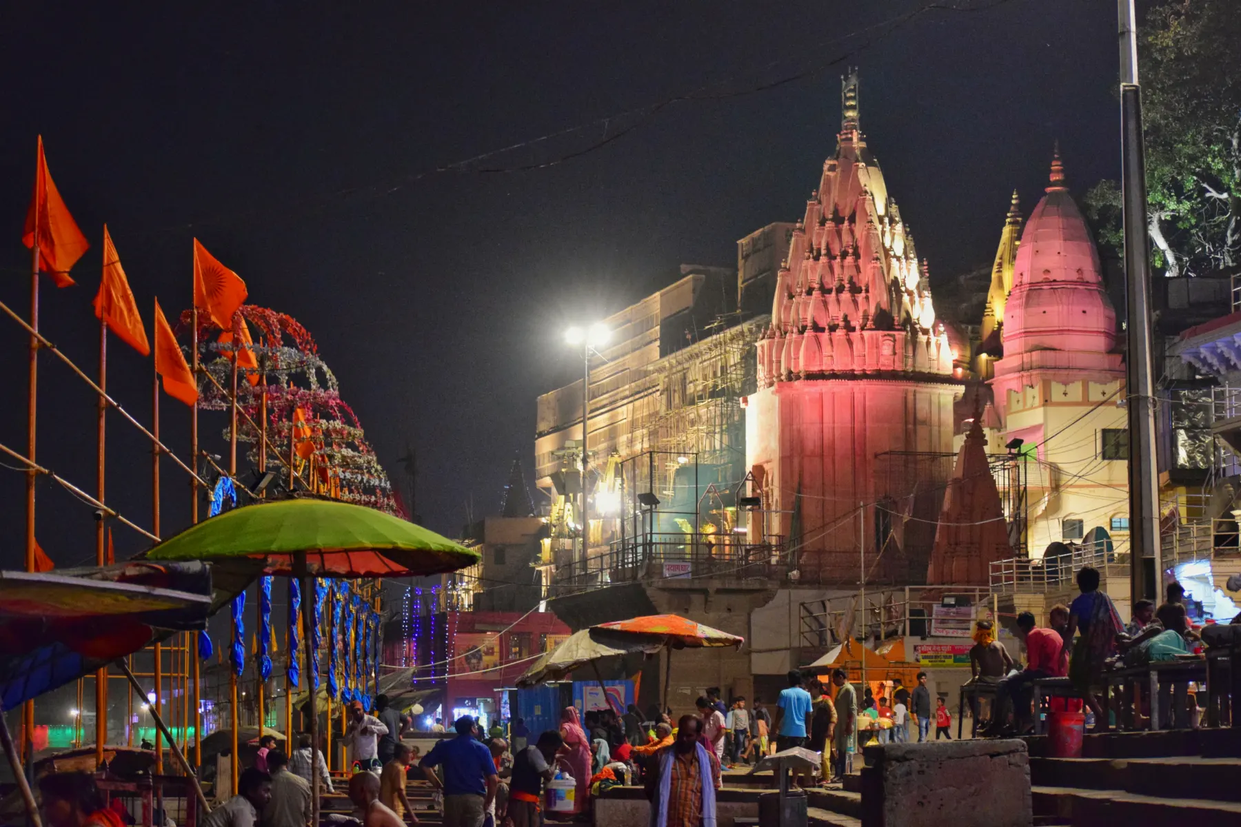 Riverside temples and saffron flags lit up at night