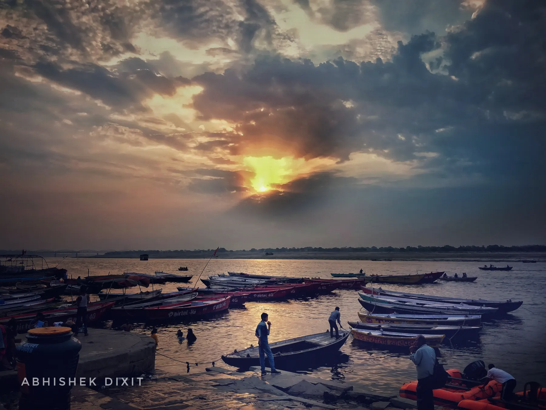 Sunrise breaking through clouds over boats on the Ganga